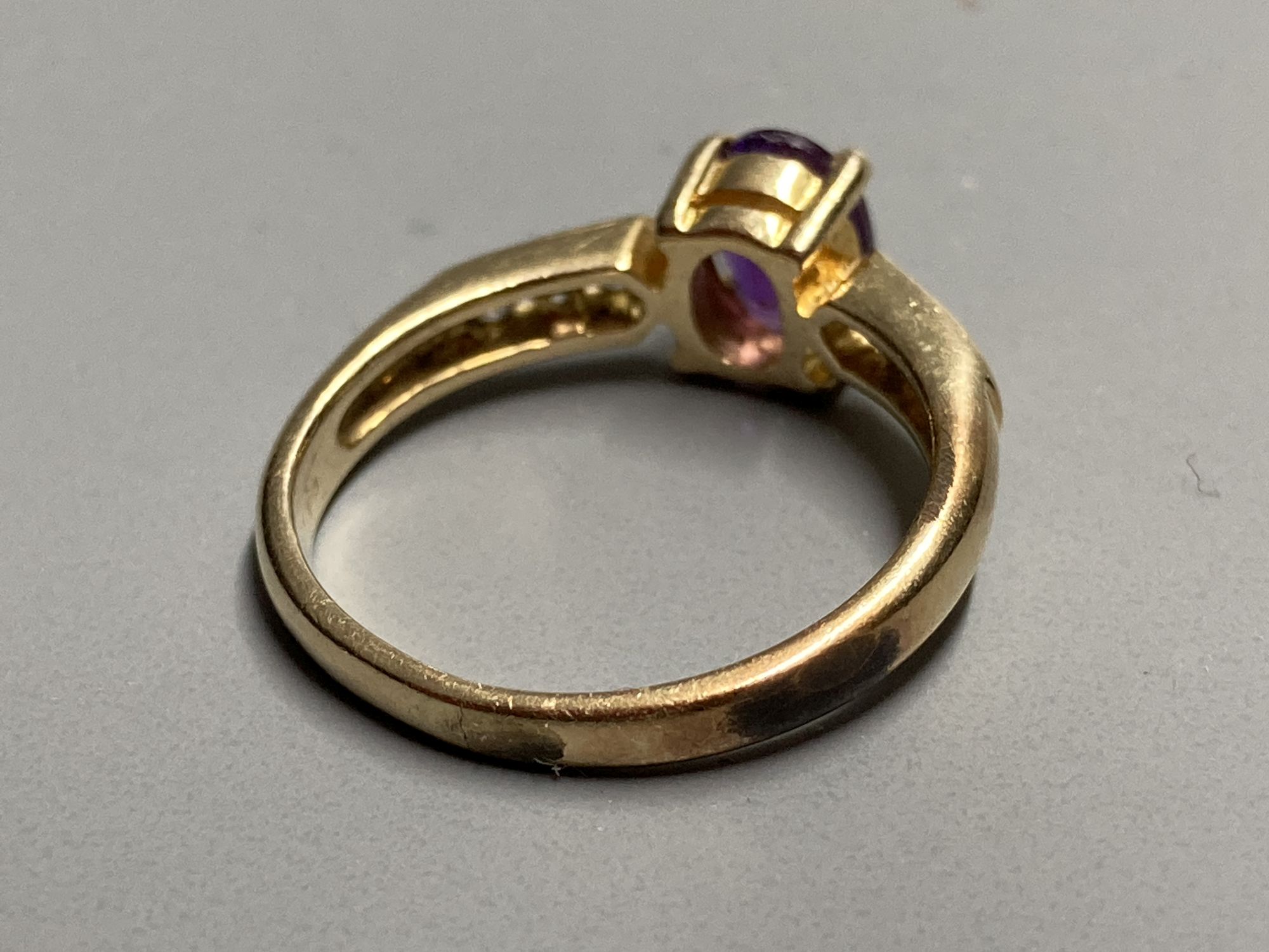 A modern yellow metal, amethyst ring with white stone (possibly white sapphire) set shoulders, size L, gross 2.7 grams.